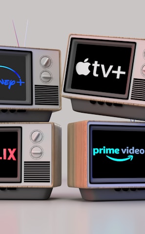 Four old-style television sets are stacked in two rows and each screen displays a different streaming service logo: Disney+, Apple TV+, Netflix, and Prime Video.